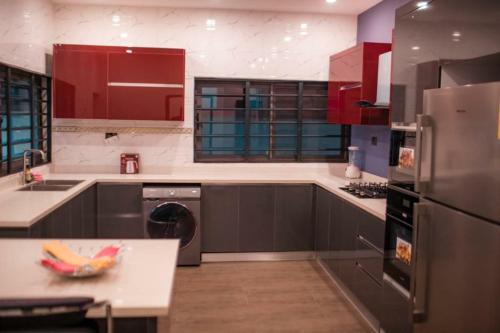 a kitchen with red cabinets and a stainless steel refrigerator at Luxe Vista Villa in Kumasi