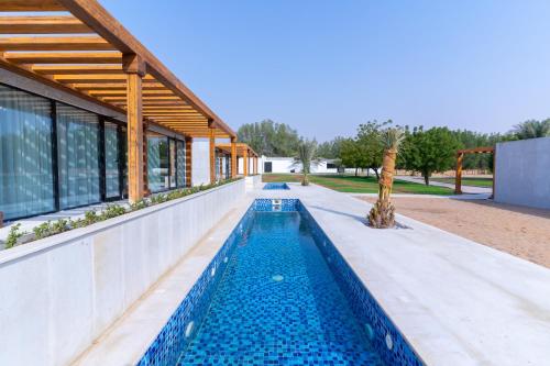 - une piscine en face d'une maison dans l'établissement AL JUNAIDI FARM BY BRIDGE RETREATS, à Charjah