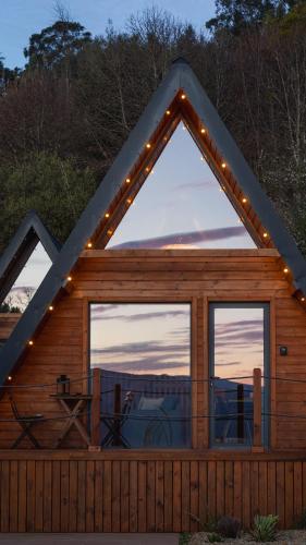 a log cabin with a large window with lights at Casas da Madrinha in Arcos de Valdevez