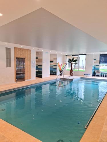 une piscine avec de l'eau bleue dans un immeuble dans l'établissement Résidence Services Séniors - Domitys Les Jardins d'Ahna, à Dinan