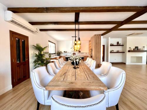 une salle à manger avec une table en bois et des chaises blanches dans l'établissement AL JUNAIDI FARM BY BRIDGE RETREATS, à Charjah