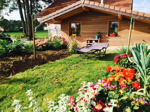 a garden with a house with a chair and flowers at Gîte Les Cigognes in Orchamps-Vennes