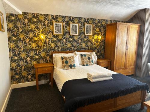 a bedroom with a bed and a wall covered in wallpaper at The Golden Fleece Inn in Porthmadog