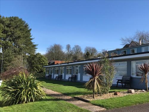 a building with windows and plants in a yard at Brixham Holiday Park Gold 2 Bedroom Holiday Home in Brixham