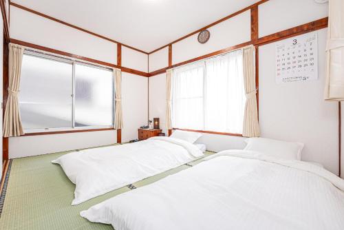two beds in a room with a window at Himawari in Tokyo