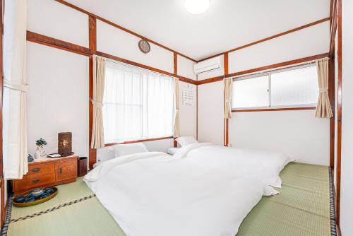 une chambre avec deux lits et deux fenêtres dans l'établissement Himawari, à Tokyo