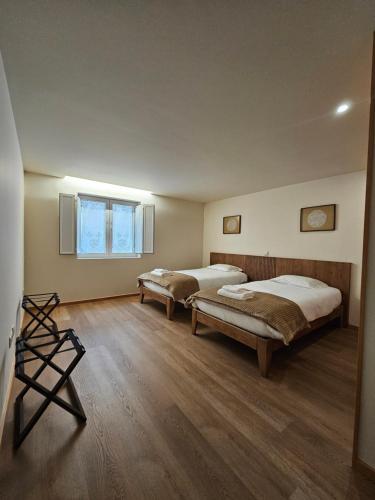 two beds in a room with wooden floors and a window at BUTEKO HOUSE AL in Miranda do Douro