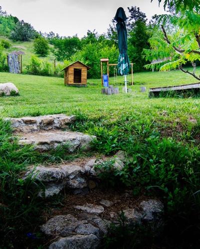 a garden with a umbrella and a wooden shed at Cob Village in Berca