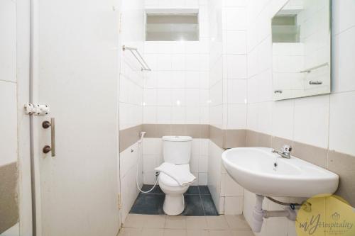 a white bathroom with a toilet and a sink at Fortuna Hotel & Residence by My Hospitality in Bandung