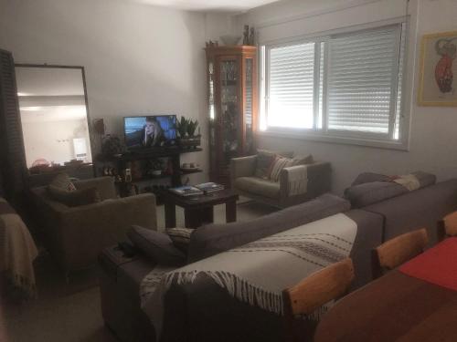 a living room with couches and a tv and a mirror at Studio Residencial Montevideo in Osório