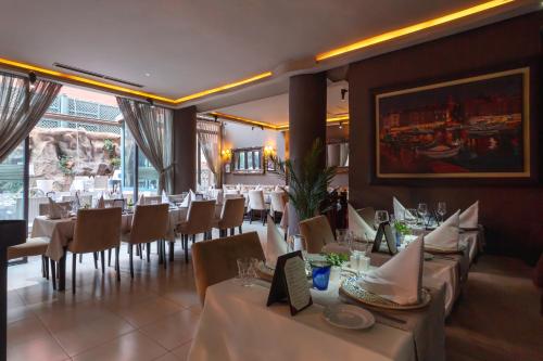a restaurant with white tables and chairs and a painting at Le Caspien Boutique Hotel in Marrakech
