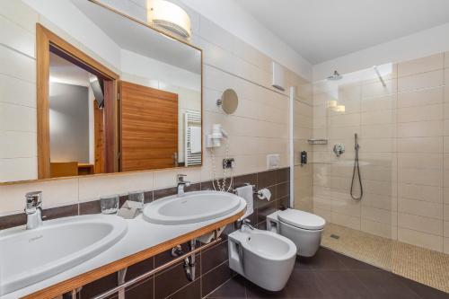 a bathroom with a sink and a toilet and a mirror at Family Hotel Adriana in Ledro