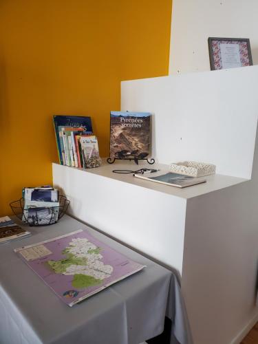 une table avec une étagère, des livres et une carte dans l'établissement Studio cosy classé 3 étoiles dans cœur historique, à Arreau