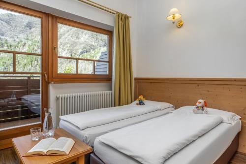 two beds in a room with a window at Family Hotel Adriana in Ledro