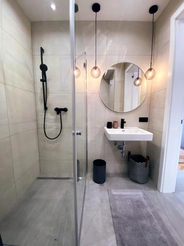 a bathroom with a shower with a sink and a mirror at Stylische Wohnung mit Balkon in Graz