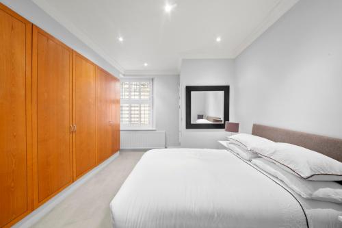 a white bedroom with a large bed and wooden cabinets at South Kensington Luxury Suite in London