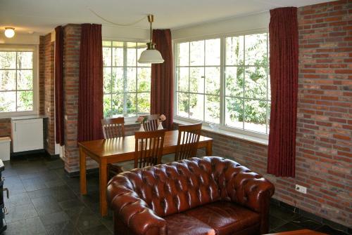 a living room with a leather couch and a table at Bungalowpark Bij de Bronnen in Nutter