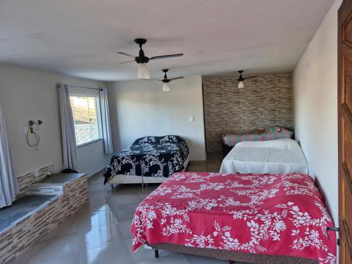 a bedroom with two beds and a ceiling fan at Suite para familia! in Saquarema