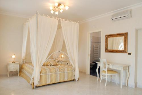 a bedroom with a canopy bed and a desk at Villa Caramia in Locorotondo