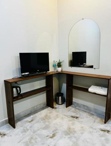 a desk with a television and a mirror in a room at 4D's Coast,Vagator in Vagator