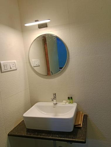 a bathroom with a white sink and a mirror at 4D's Coast,Vagator in Vagator
