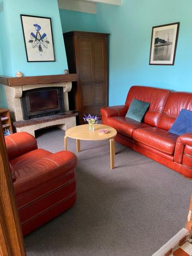 ein Wohnzimmer mit einem roten Ledersofa und einem Tisch in der Unterkunft 31 Chemin de la Croix aux Outils in Paimpol