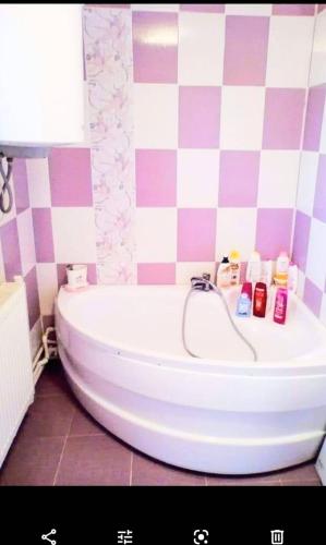 La salle de bains est pourvue d'une baignoire blanche et d'un mur en damier. dans l'établissement Casa Eva și Ioan, à Corbu