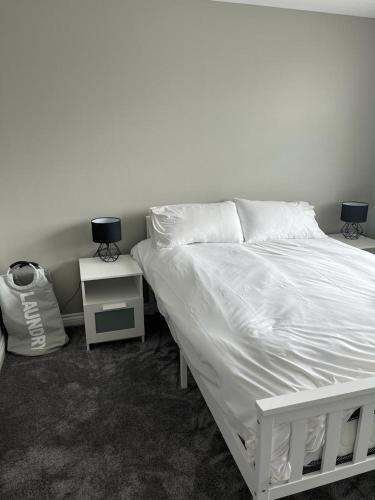 a bedroom with a white bed and a night stand at Thornaby Apartment in Thornaby on Tees