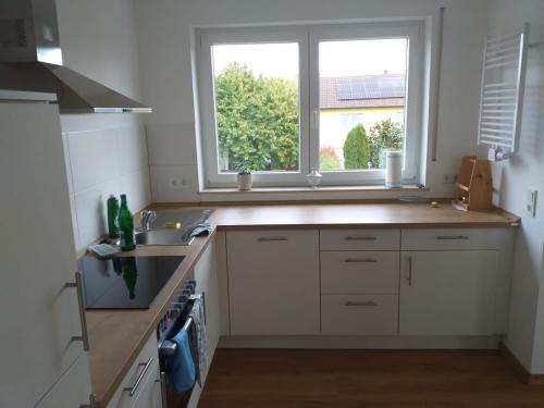 a kitchen with white cabinets and a sink and two windows at Helle 4 ZKB mit Balkon in Wittlich in Wittlich
