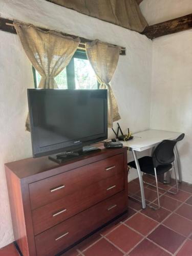 TV en la parte superior de un tocador con escritorio y mesa con en CASITA CAMPESINA A 20 MIN DE SOGAMOSO, en Sogamoso