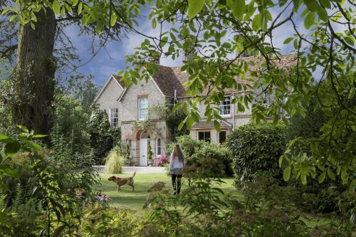 a woman walking in front of a house with a dog at Rectory Manor in Lavenham