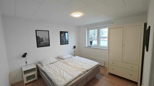 a white bedroom with a bed and a window at Sommerhus ved strand og lystbådhavn Søby - Ærø in Søby