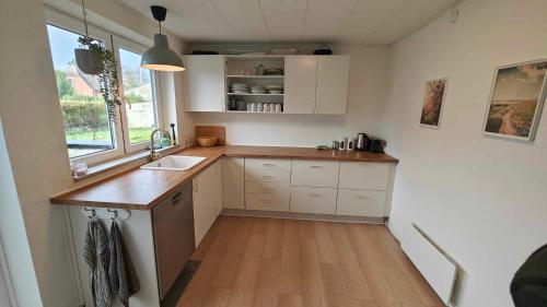 a kitchen with white cabinets and a sink and a window at Sommerhus ved strand og lystbådhavn Søby - Ærø in Søby