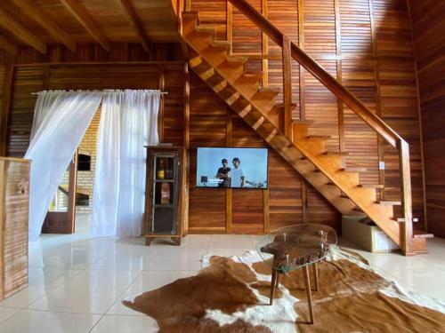 un salon avec un escalier et une télévision dans l'établissement Chalé Vô Vilbertinho, pousada com café da manhã!, à Alfredo Wagner