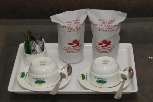 a tray with two tea cups and spoons on it at Sun River Resort in Dogadda
