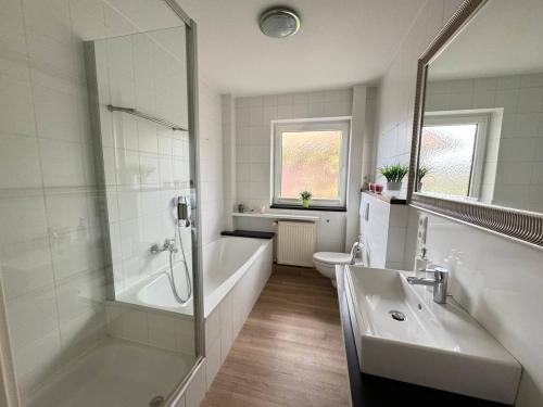 a bathroom with a tub and a sink and a shower at Central City Apartment Cloppenburg in Cloppenburg