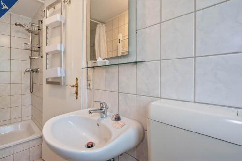 une salle de bain blanche avec un lavabo et une baignoire dans l'établissement Ferienresort Möwenort Lütow Bungalow 8, à Lütow