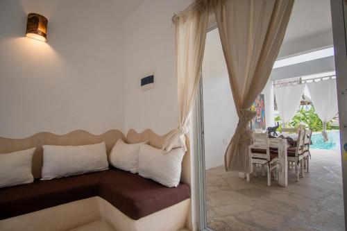 a bedroom with a couch and a table with a dining room at Rafiki Tamu Residential Resort in Watamu