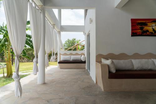 a porch with white curtains and a swing at Rafiki Tamu Residential Resort in Watamu