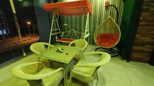 eine Terrasse mit einem Tisch, Stühlen und einer Schaukel in der Unterkunft Swastik Vatika in Ambāla