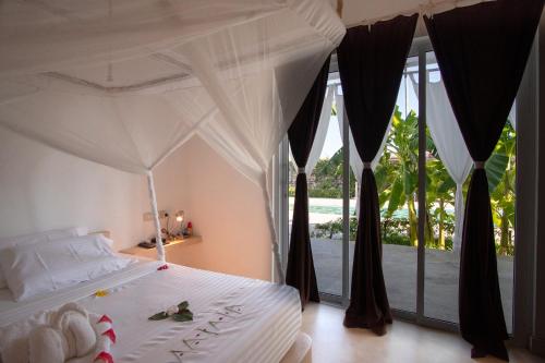 a bedroom with a white bed with a view of the ocean at Rafiki Tamu Residential Resort in Watamu