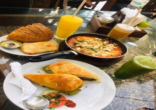 Hotel Golden Saffron - Punjabi Bagh Delhi في نيودلهي: طاولة مع أطباق من الطعام ومقلاة من الطعام