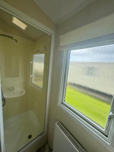 een badkamer met een douche, een wastafel en een raam bij Atlas festival in Leysdown-on-Sea