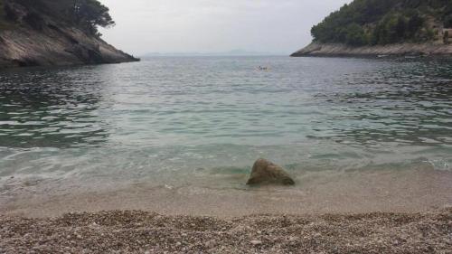 a rock in the sand on a beach near the water at Rustical Apartment in Korčula
