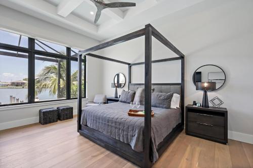 een slaapkamer met een hemelbed en grote ramen bij Luxurious home with pool/spa and huge water view in Marco Island