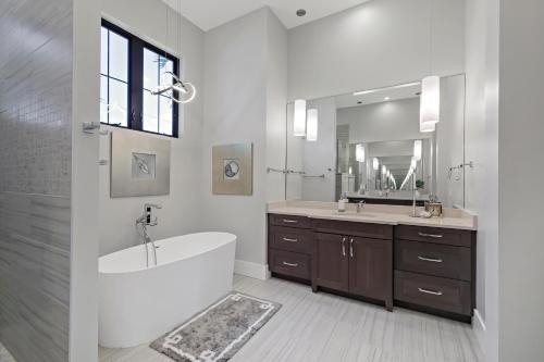 een badkamer met een bad, een wastafel en een spiegel bij Luxurious home with pool/spa and huge water view in Marco Island