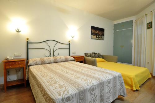 Habitación de hotel con 2 camas, escritorio y cama en Hotel Apartamentos Aralso Sotillo, en La Lastrilla