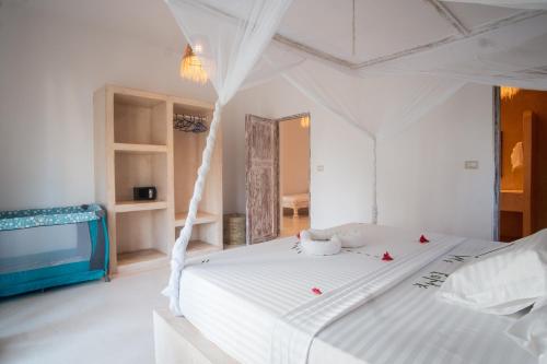 a white bedroom with a large white bed with red pillows at Rafiki Tamu Residential Resort in Watamu