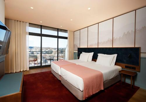 Montebelo Viseu Congress Hotel في فيزيو: غرفة نوم بسرير كبير ونافذة كبيرة