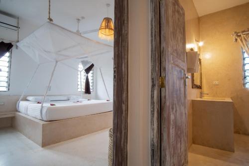 a bedroom with a white bed with a canopy at Rafiki Tamu Residential Resort in Watamu